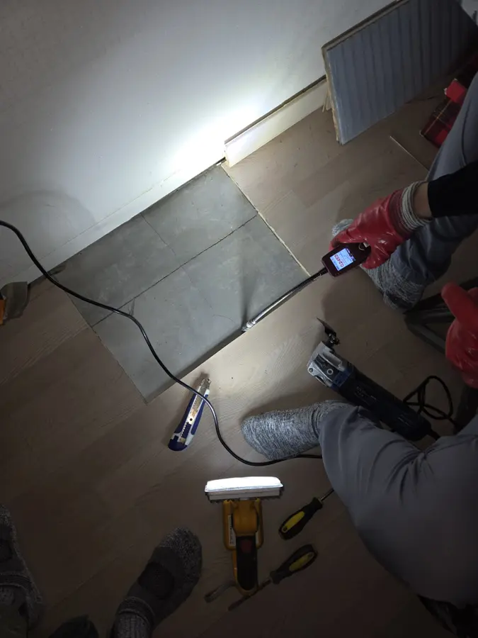 마루 한 칸을 걷어낸 자리에서 작업자가 장비를 대고 배관 상태를 확인하는 모습